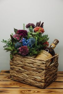 bouquet of flowers with whisky bottle in woven basket